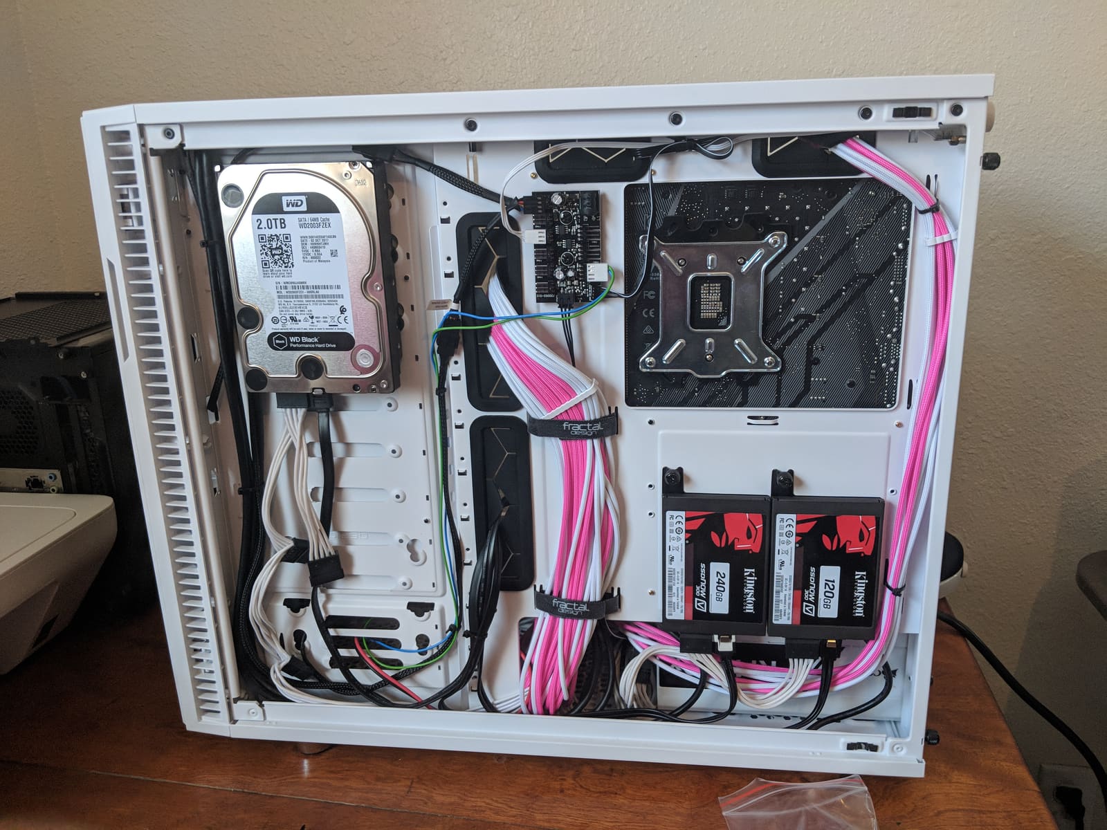 The back of the case with pink and white cables routed and tied down behind the motherboard tray