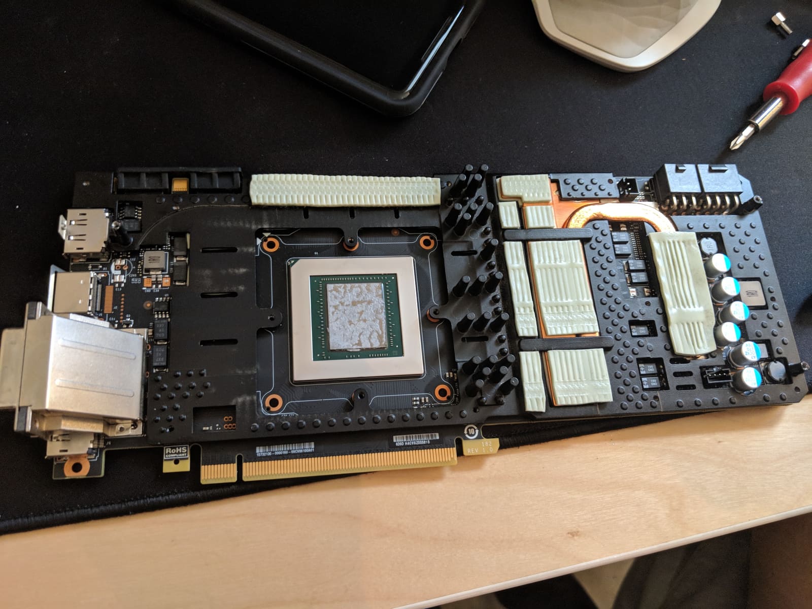 The GTX 1080 Ti with its air cooler removed, showing the bare GPU die, memory, and old thermal pads