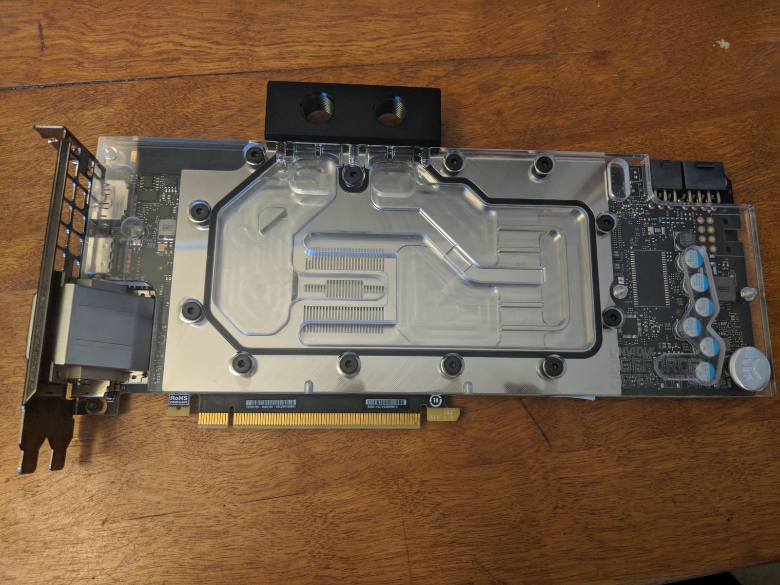 The GTX 1080 Ti with the EK water block installed, lying on a wooden desk